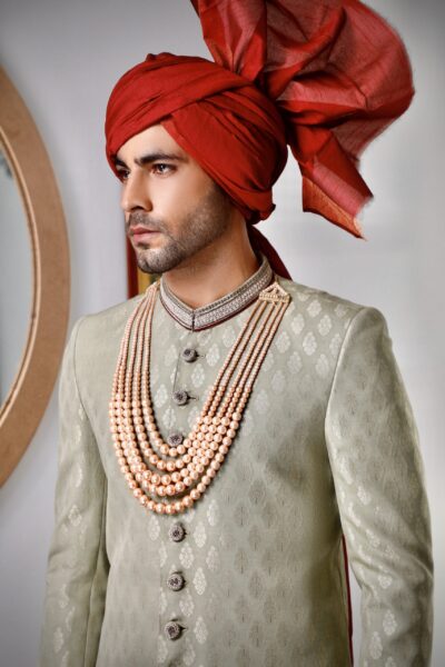mint green self-weaved sherwani with delicate embroidery accented in maroon, paired with a matching maroon turban