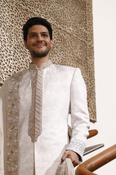 elegant white sherwani with embroidery on the front border, paired with a matching inner suit and a four-sided embroidered shawl, perfect for the modern groom.