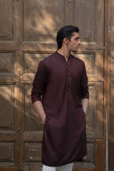 man wearing a luxury burgundy wine-toned kurta for men with subtle metallic beadwork on the collar,