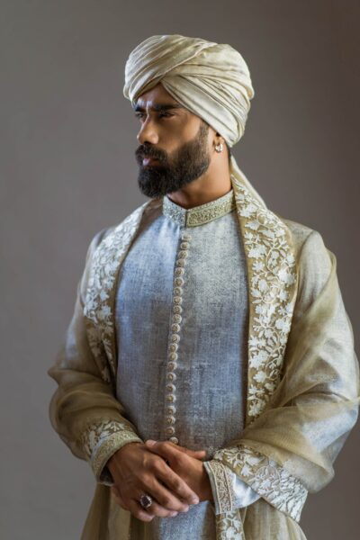Graceful groom wearing white sherwani for men designed by Naushemian by Nauman Arfeen paired with matching turban and shawl and groom accessories