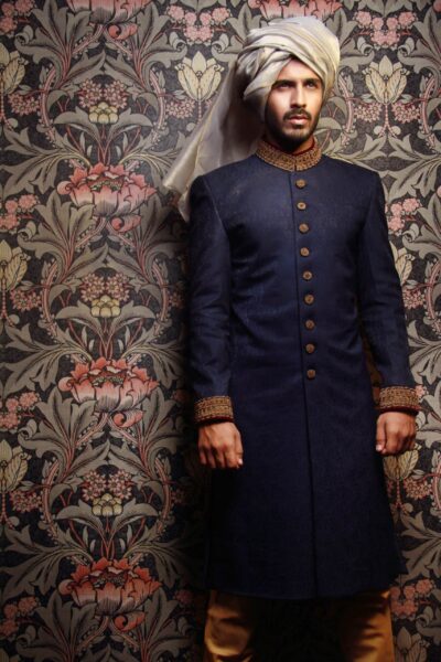 man wearing DENIM BLUE SHERWANI PAIRED WITH BROWN INNER SUIT AND BEIGE TURBANDENIM BLUE SHERWANI for groom PAIRED WITH BROWN INNER SUIT AND BEIGE TURBAN designed by naushemian by nauman arfeen