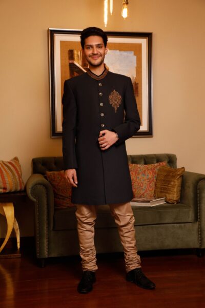 man wearing BLACK SHERWANI for groom PAIRED WITH GOLDEN INNER SUIT on his wedding day by naushemian by nauman arfeen