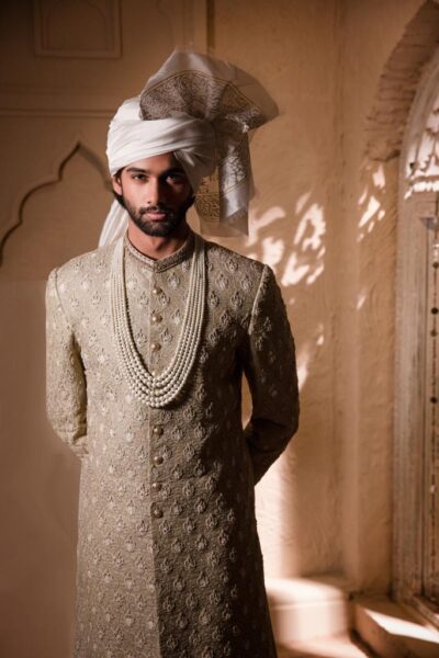 man wearing ARTICHOKE GREEN SHERWANI WITH MATCHING INNER SUIT PAIRED WITH WHITE TURBAN AND SHAWL of naushemian by nauman arfeen - SHERWANI SET IN PAKISTAN