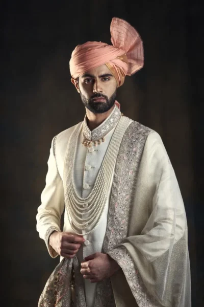 CREAM OFF-WHITE SHERWANI WITH MATCHING INNER SUIT, AND SHAWL PAIRED WITH PASTEL PEACH TURBAN