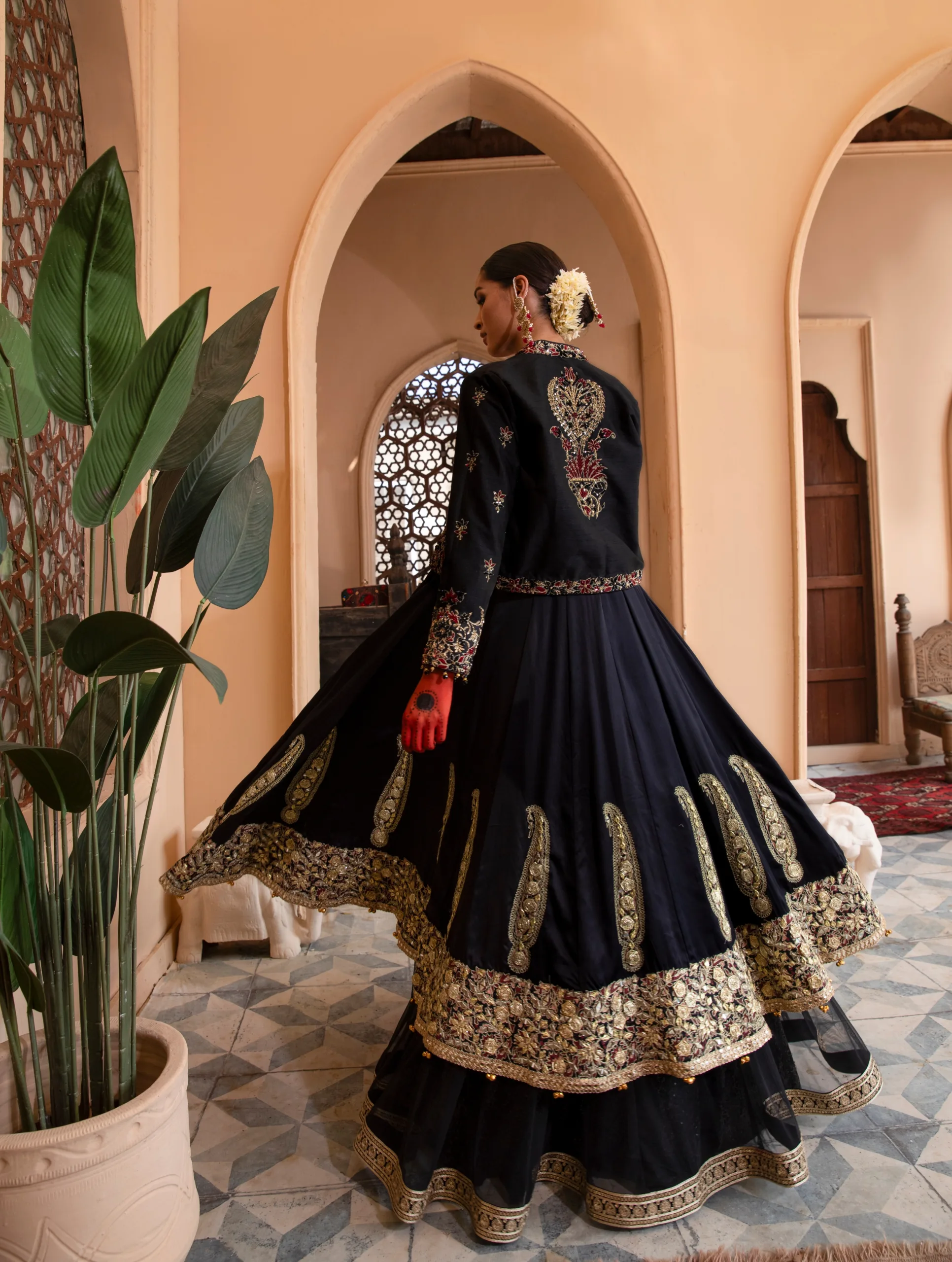 B612_20240419_185356_001 A luxurious black dress with cascading net layers, adorned with intricate embroidery and gota kinara work
