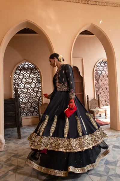 A luxurious black dress with cascading net layers, adorned with intricate embroidery and gota kinara work