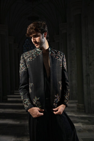 Imperial Vine Black Embellished Couture Prince Coat Set featuring intricate floral vine embroidery, multicolour crystal embellishments, mandarin collar, black inner kurta, and draped trousers. ÉTOILE collection by Nauman Arfeen is a story chosen to tell through fabric, craftsmanship, light and emotion. The Genesis is the first chapter of a five-part journey
