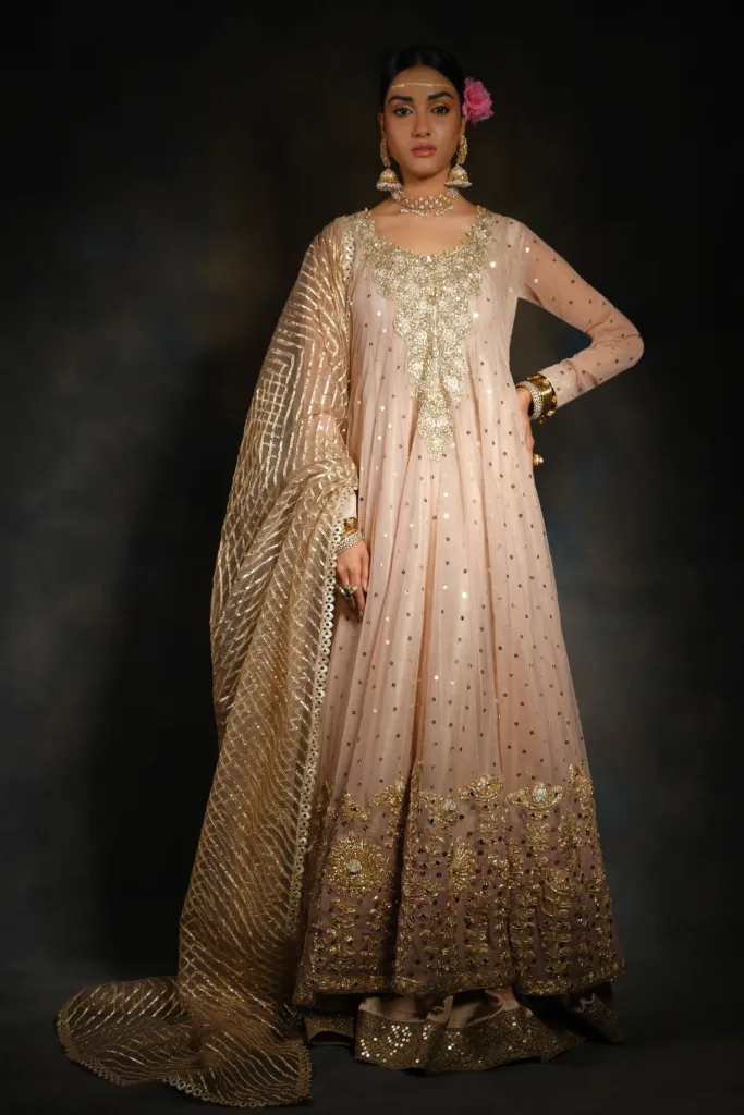 bride wearing Peach Wedding Gown with heavy embroidered gold neck work, mirror work on the full frock, and a heavily embroidered dupatta with floral lace work and heavy borders.