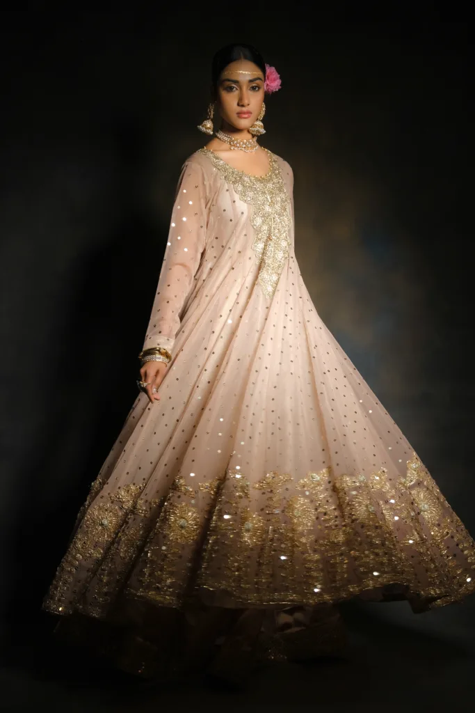 bride wearing Peach Wedding Gown with heavy embroidered gold neck work, mirror work on the full frock, and a heavily embroidered dupatta with floral lace work and heavy borders.