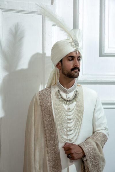 Pakistani WHITE sherwani by Naushemian Nauman Arfeen – Divinus masterpiece design featuring intricate Kora embroidery, filigree detailing, embroidered shawl, regal turban, and handcrafted Khoosa shoes for luxury weddings