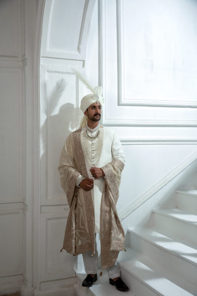 Pakistani WHITE sherwani by Naushemian Nauman Arfeen – Divinus masterpiece design featuring intricate Kora embroidery, filigree detailing, embroidered shawl, regal turban, and handcrafted Khoosa shoes for luxury weddings