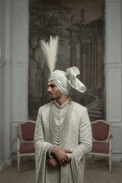 Pearl-Embellished White Sherwani for Groom by Naushemian with intricate hand embroidery, pearl detailing on collar, buttons, sleeves, paired with matching inner suit, kurta, turban and four-sided embroidered shawl luxury wedding attire