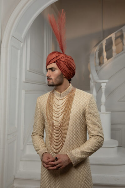 Royal Sherwani for Groom 2025 by Nauman Arfeen – Luxury Pakistani Wedding Sherwani in traditional heritage design with embroidery and prince coat styleÉlysian Luxe Sherwani for Groom in light gold with hand embroidery on collar and sleeves, back motif, matching inner suit and turban – luxury Pakistani wedding sherwani