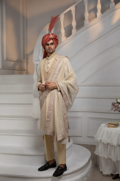 alt="Auric Majestic Sherwani for Groom in gold with intricate thread embroidery, fine hand embellishments on collar front and sleeves, luxury wedding sherwani by Naushemian