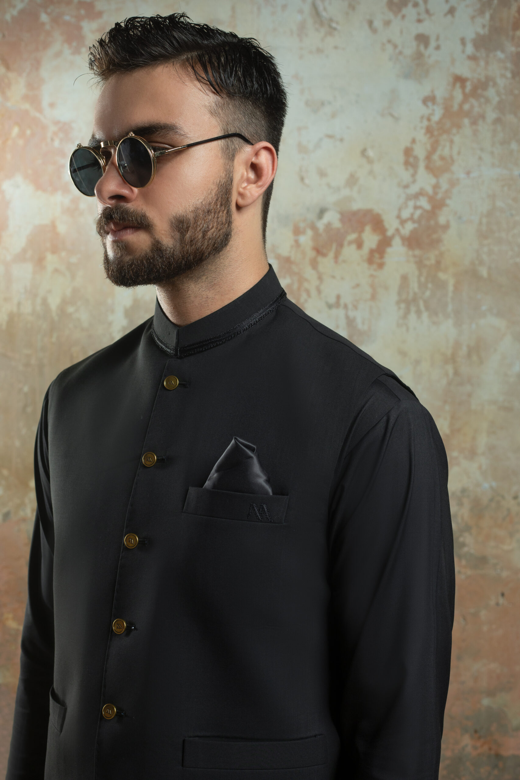 NA SIGNATURE BLACK WAISTCOAT FOR MEN by Naushemian by Nauman Arfeen. Model wearing formal Nehru Vest with Premium Gold Buttons (NA detail) over Kurta Pajama set. Ideal Mens Wedding Attire accessory