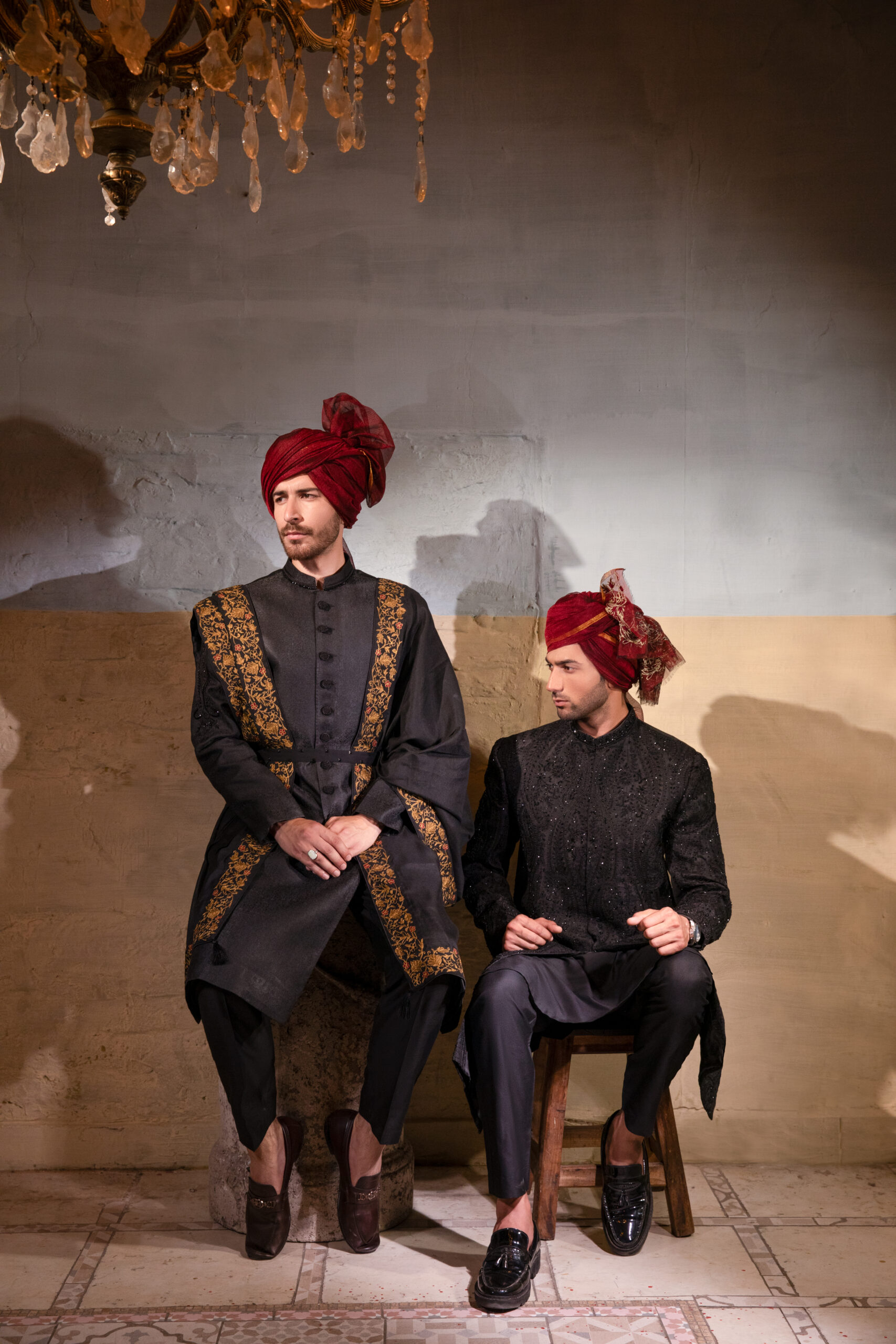 Artisan crafted black sherwani with embroidered collar and buttons, paired with black-maroon-gold shawl and maroon turban