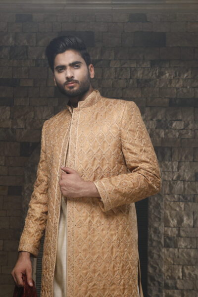 Striking camel gold sherwani meets a beige inner suit for a trendy twist. A maroon shawl adds a pop of color, making this outfit perfect for a wedding. Grab the best of Naushemian by Nauman Arfeen